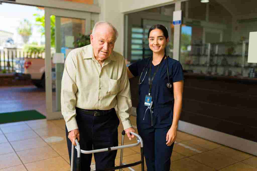 Portrait of a female smiling nurse helping a happy older mature man with a walker taking a walk around the nursing home